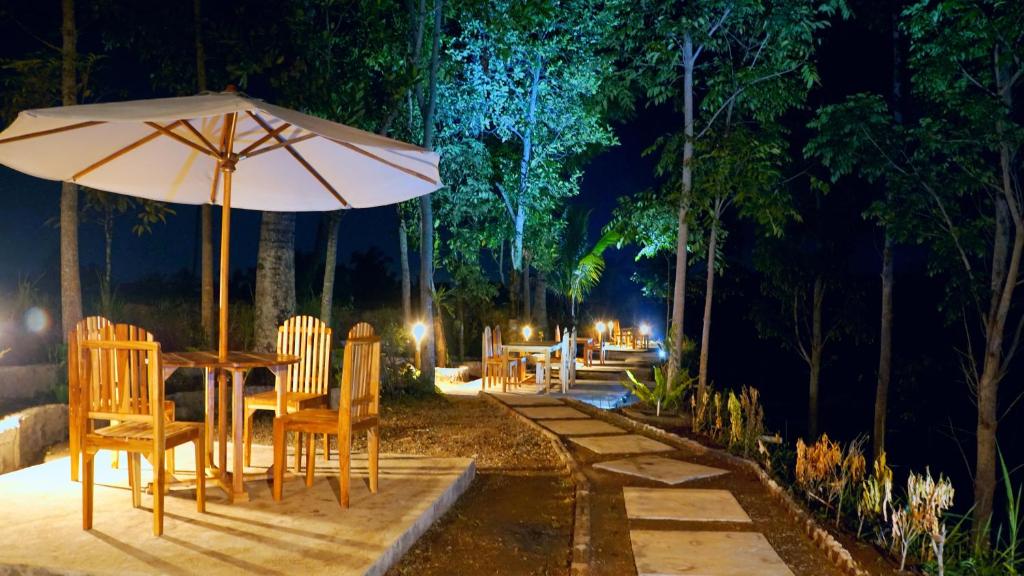 特特巴图Vanilla Garden的一张桌子和椅子,晚上带雨伞