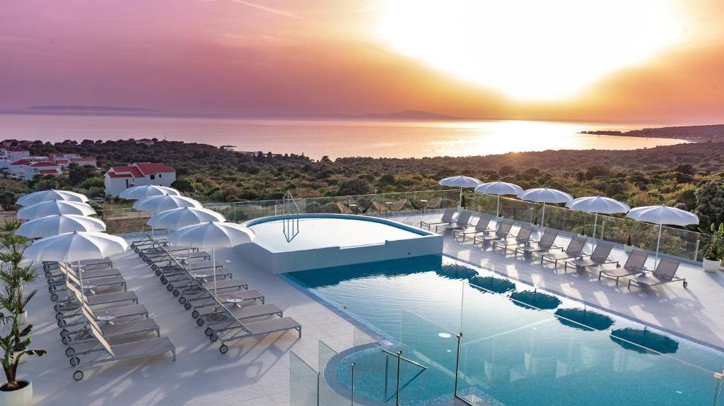 诺瓦利娅Hotel In Excelsis的一个带游泳池和椅子的度假胜地和大海