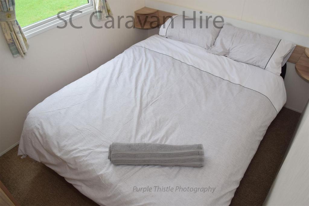 爱丁堡3 Bedroom at Seton Sands Caravan Hire的一张带白色床单和枕头的床以及窗户