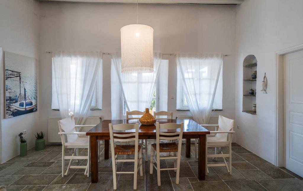 ExámbelaPlakoto House的一间带木桌和白色椅子的用餐室