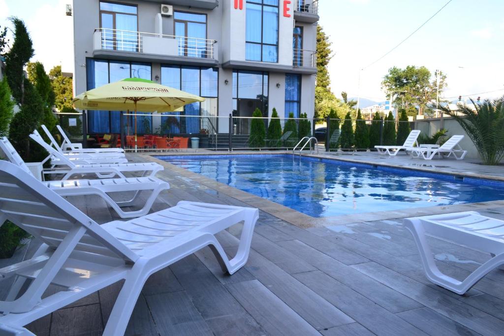 巴统Hotel Skyline Batumi的一座带椅子和遮阳伞的游泳池位于大楼旁