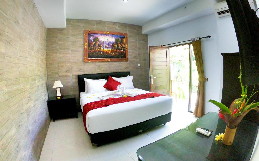 努沙杜瓦棕榈竹酒店的卧室配有带红色枕头的大型白色床