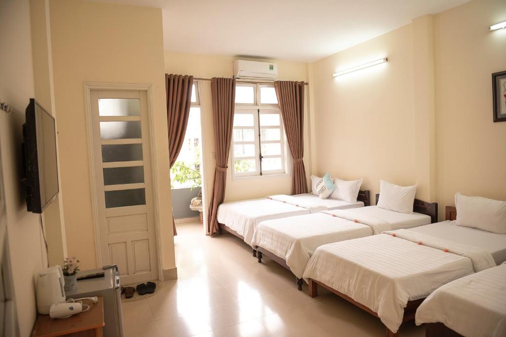 顺化明丹旅馆的一间卧室设有三张床和窗户。