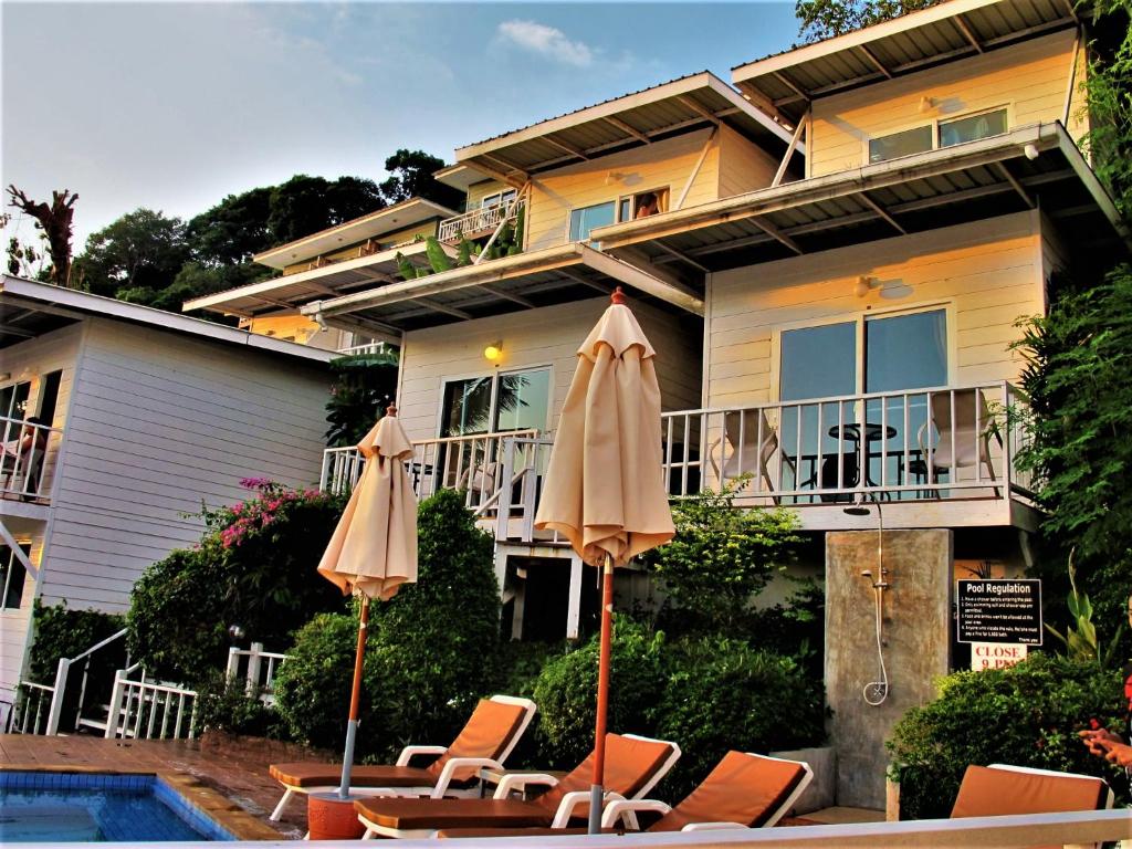 皮皮岛上坡村舍酒店的游泳池旁带椅子和遮阳伞的房子