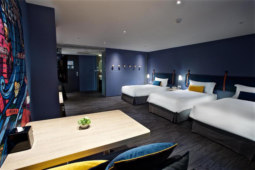 台北捷丝旅西门町馆的酒店客房设有两张床和一张桌子。