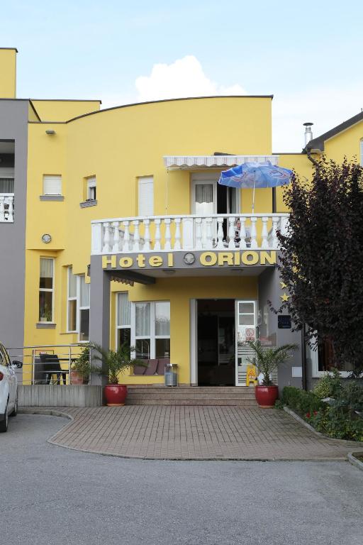 Ivanec奥里昂酒店的黄色建筑,设有酒店入口和雨伞