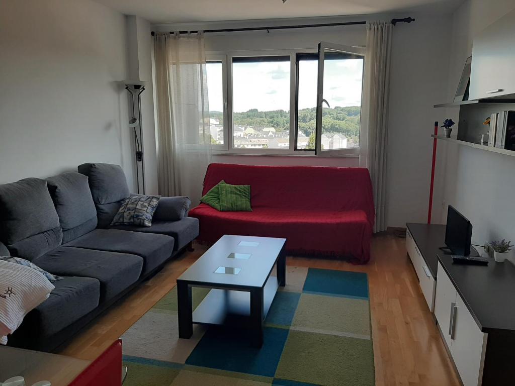 卢戈Precioso apartamento的客厅配有红色的沙发和桌子