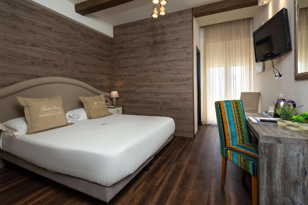 里米尼Best Western Maison B Hotel的一间卧室配有一张床、一张书桌和一台电视