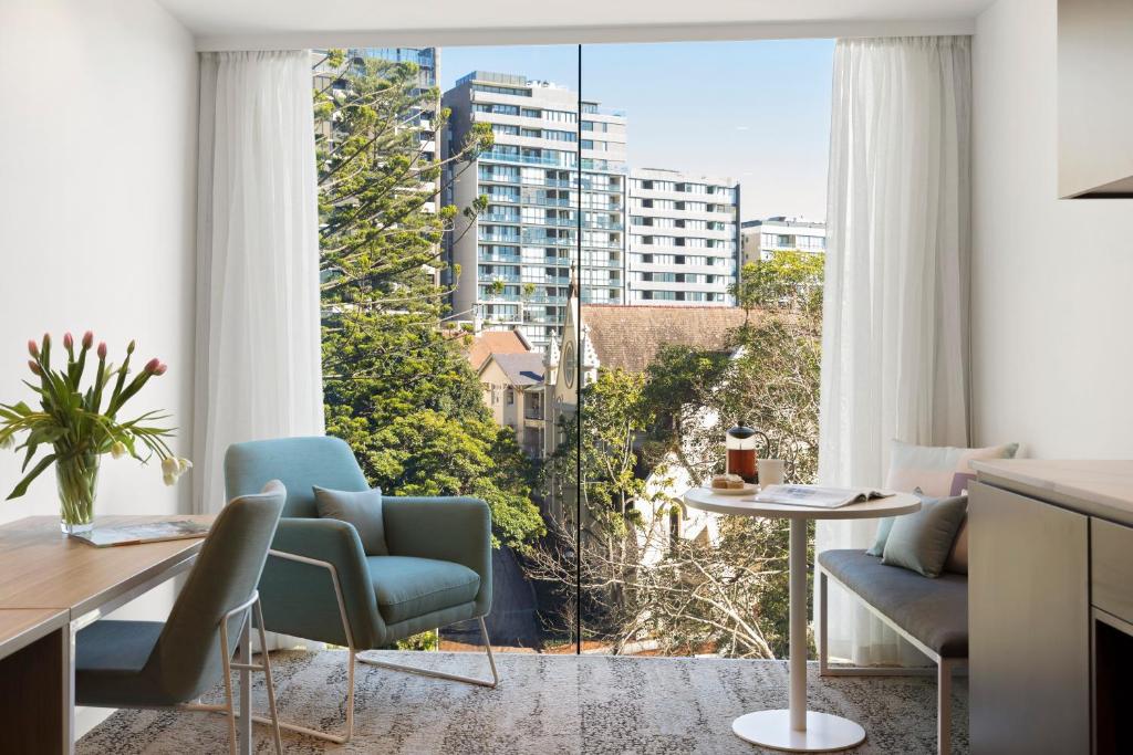 悉尼Quest North Sydney的客厅配有桌椅和大窗户