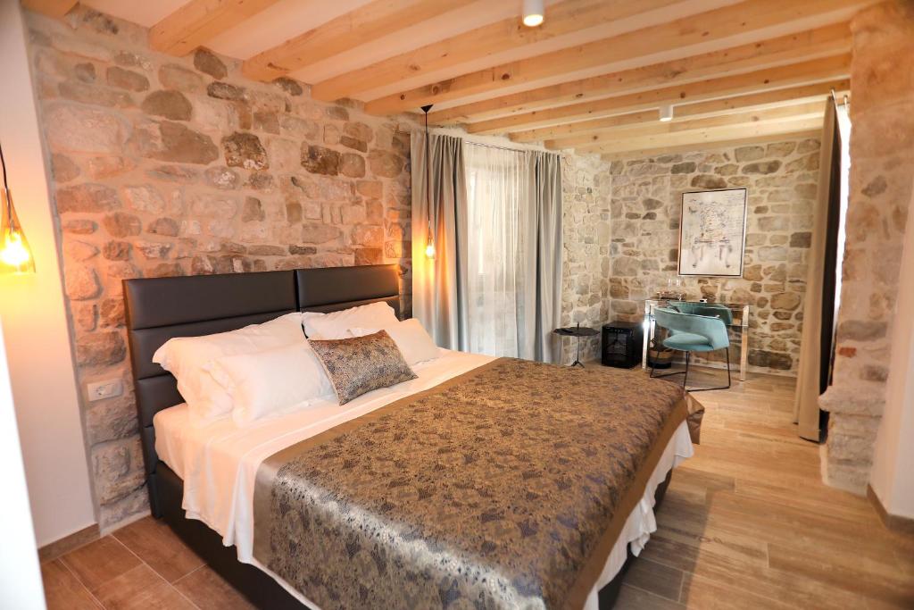 特罗吉尔Villa Teuta的一间卧室设有一张大床和石墙