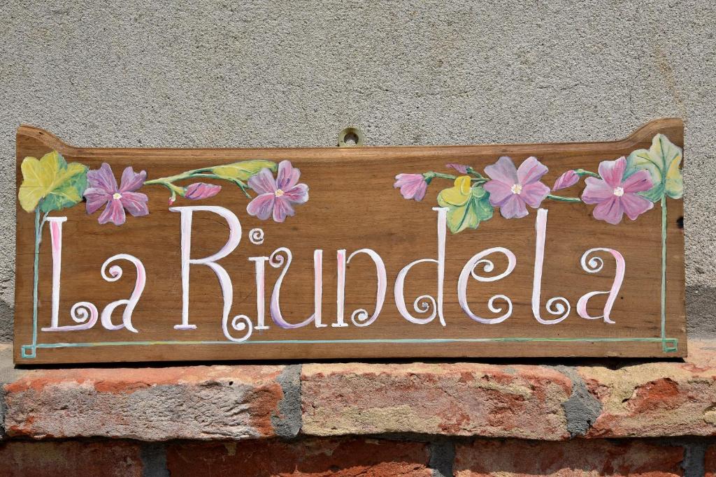 阿斯蒂B&B La Riundela的砖墙上的一个标志,上面有鲜花