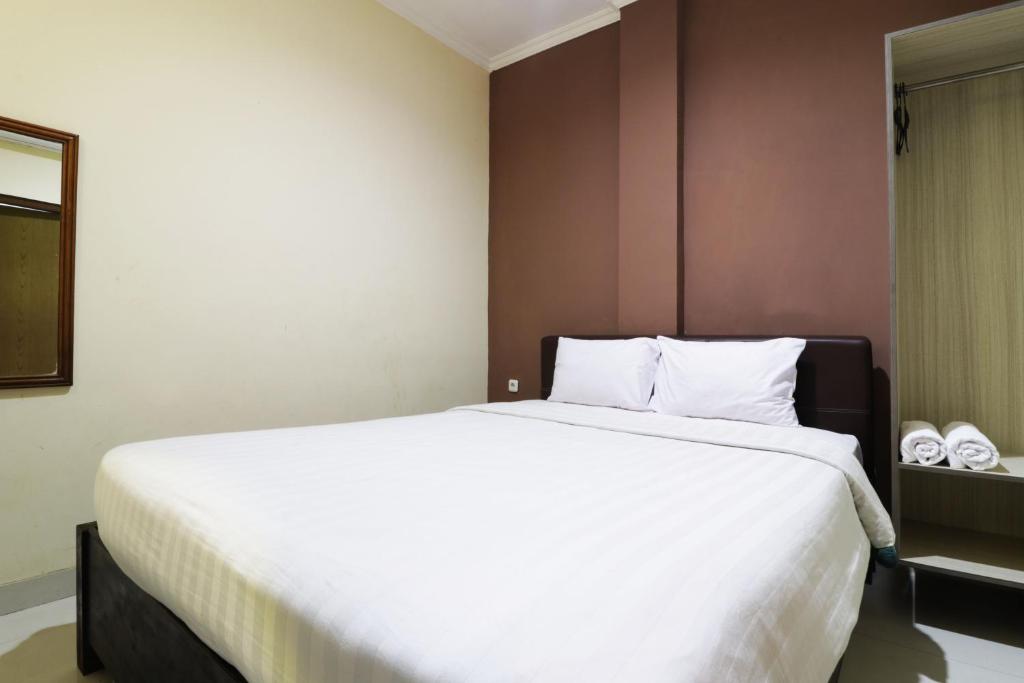 雅加达Hotel Istana Bungur的一间卧室配有一张带白色床单的大床