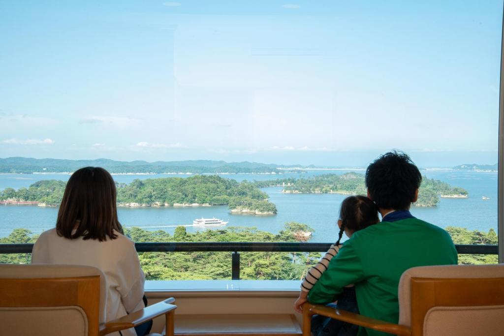 松岛町松岛大观庄度假酒店的三人组坐在俯瞰河流的阳台