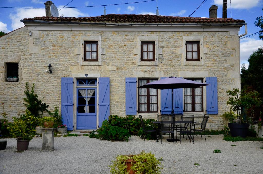 NéréChez Fins Bois的蓝色门、桌子和雨伞的房子