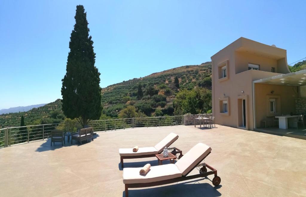 ParaspórionVilla Irini - Cretan Luxury Villa with Amazing View的一个带2把躺椅的庭院和1栋房子