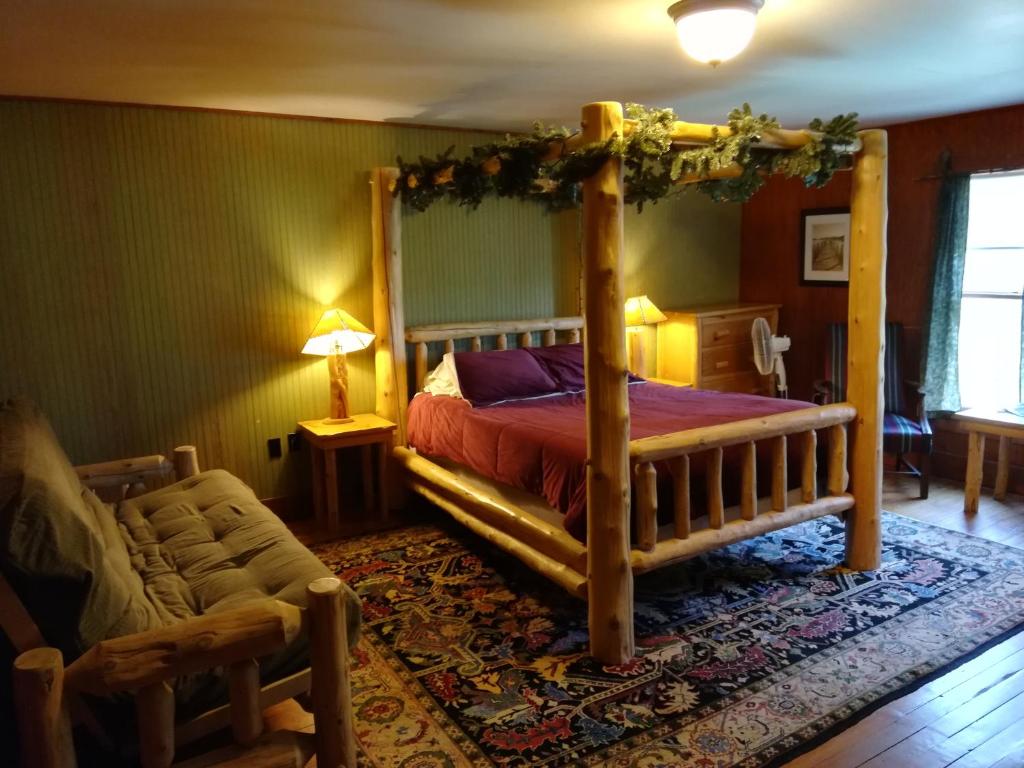 InletThe Woods Inn的一间卧室配有一张天蓬床和一把椅子