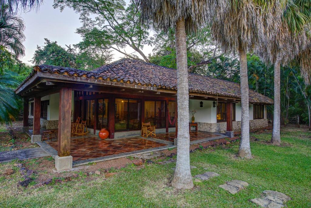 Cañas拉帕西菲卡庄园酒店的一座带门廊和两棵棕榈树的房子