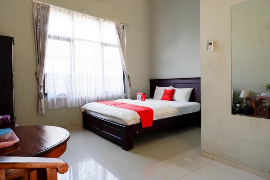 KudusRedDoorz Syariah near Menara Kudus的一间卧室配有一张带红色枕头的床和一扇窗户