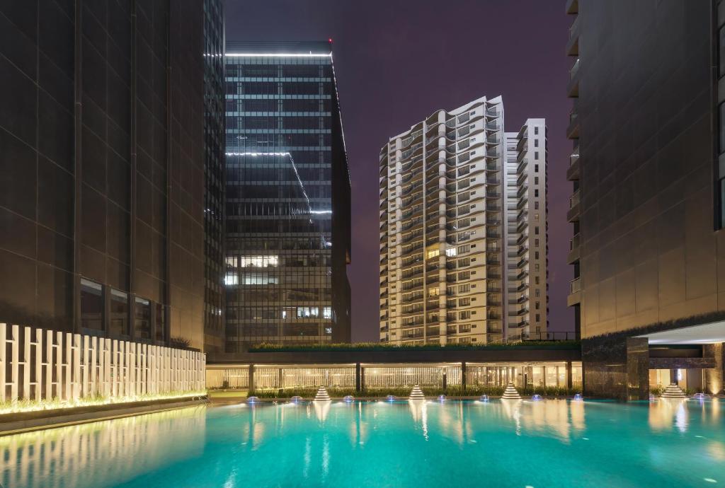 仰光Kantharyar Serviced Apartment的一座城市的游泳池,晚上有高楼