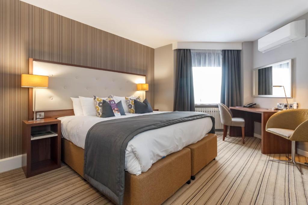 普雷斯顿Samlesbury Hotel的酒店客房设有一张大床和一张书桌。