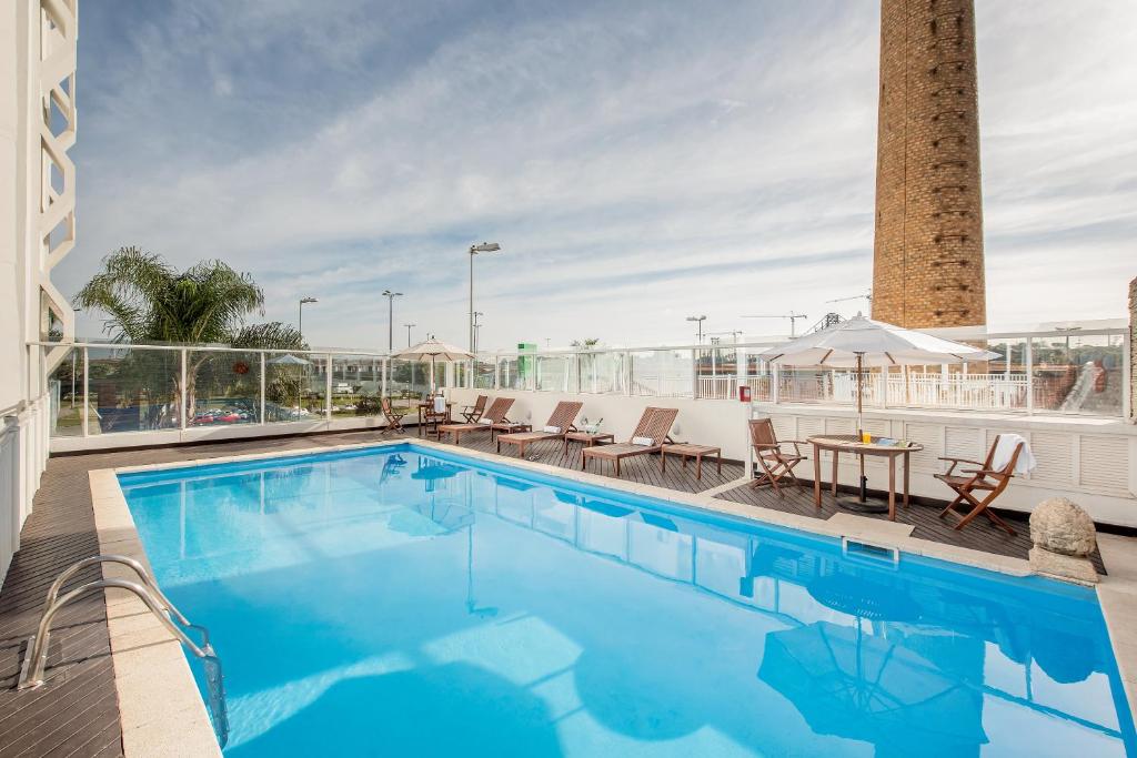 弗洛里亚诺波利斯弗洛里亚诺波利斯因特城市酒店的屋顶游泳池,配有椅子和桌子