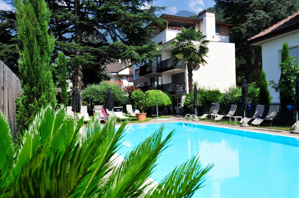 梅拉诺简诗美酒店的一座带椅子和树木的建筑前的游泳池