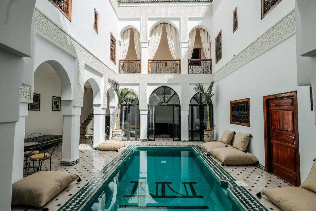 马拉喀什Riad NayaNour的一座带白色墙壁和天花板的建筑内的室内游泳池
