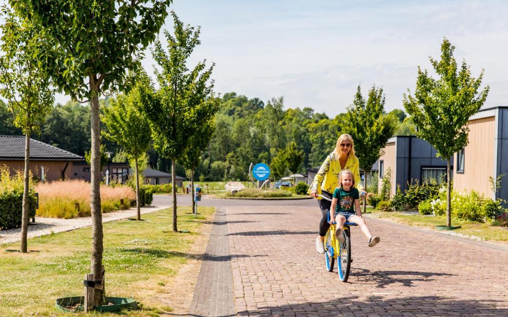 法尔肯堡TopParken – Résidence Valkenburg的一名妇女骑着自行车,带着孩子骑着自行车