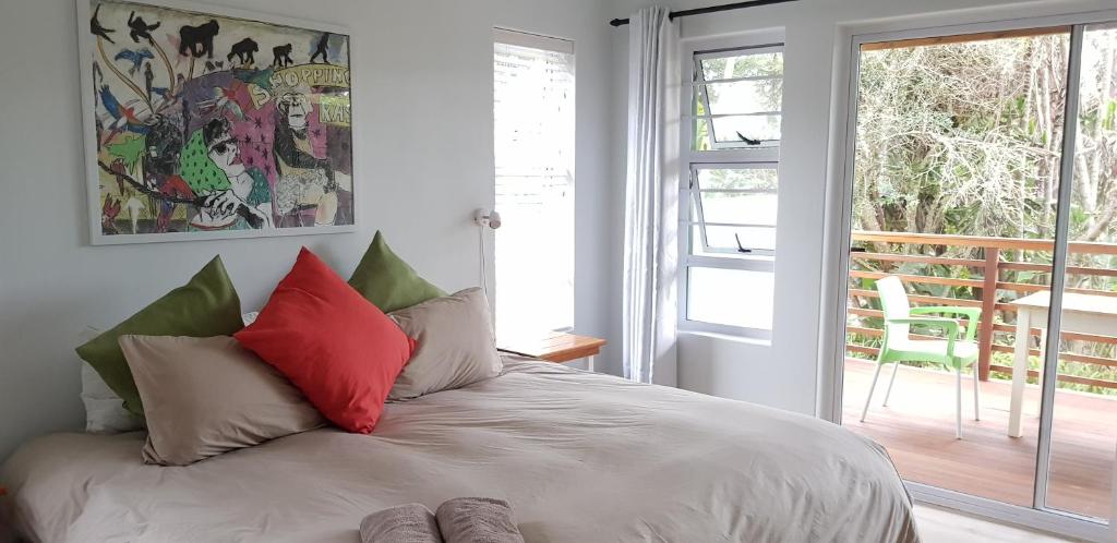 钦查Buccaneers on the beach, Chintsa, South Africa的一间卧室配有红色和绿色枕头的床