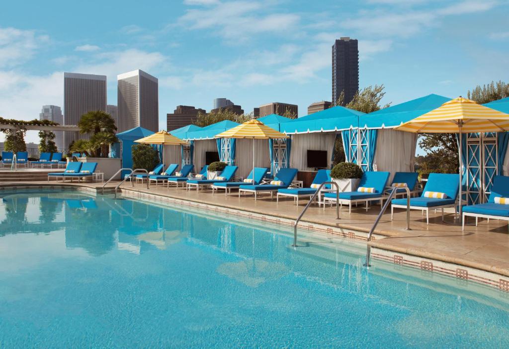 洛杉矶半岛比佛利山庄度假村的一个带蓝色椅子和遮阳伞的游泳池