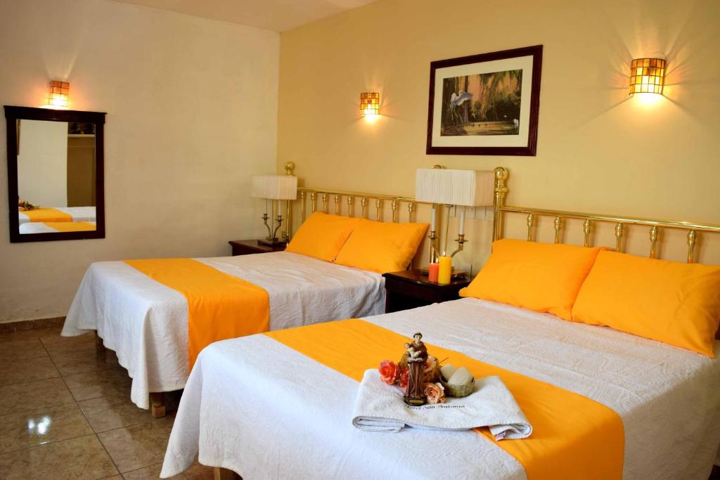 阿瓜斯卡连特斯Hotel San Antonio的酒店客房带两张带橙色床单的床