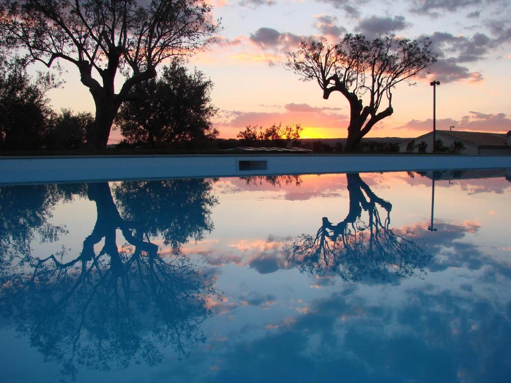 伊斯皮卡Kinanto Bioresort的日落时分在游泳池里反射树木