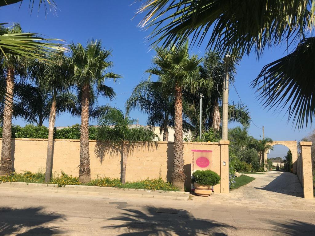 科佩尔蒂诺Villa Casole Short Lets的一条种有棕榈树和粉红色墙壁的街道