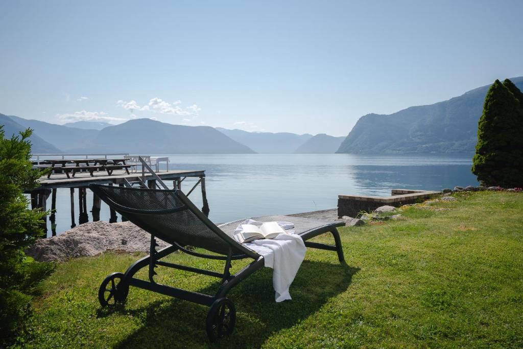 莱康厄尔Leikanger Fjordhotel - Unike Hoteller的坐在水体旁边的草上的一个长凳