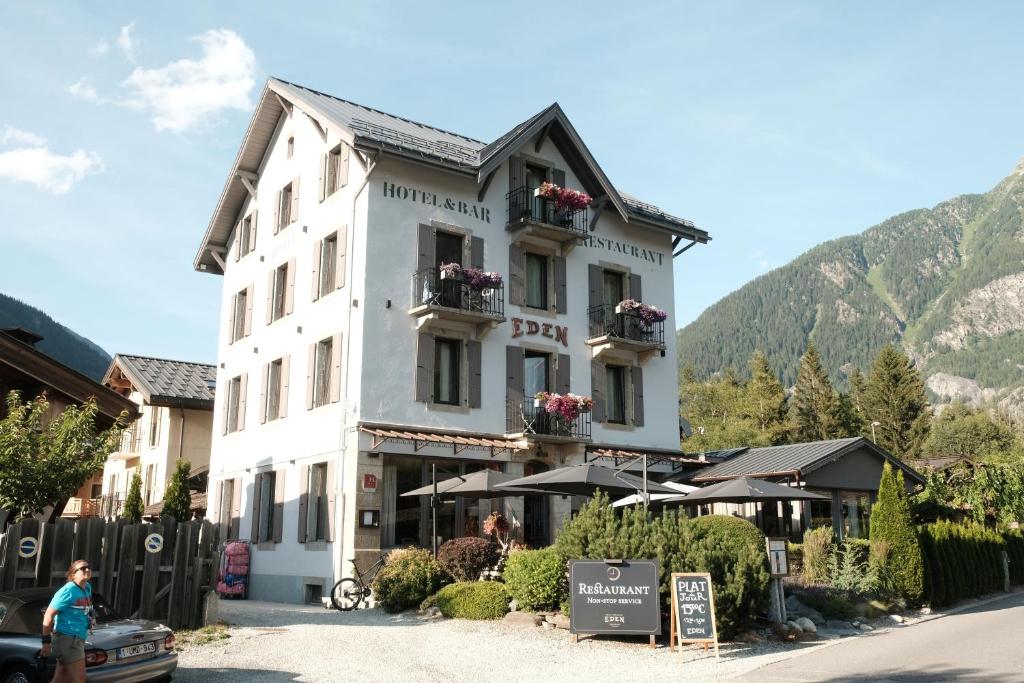 夏蒙尼-勃朗峰Eden Hotel, Apartments and Chalet Chamonix Les Praz的白色的大建筑,窗户上摆放着鲜花