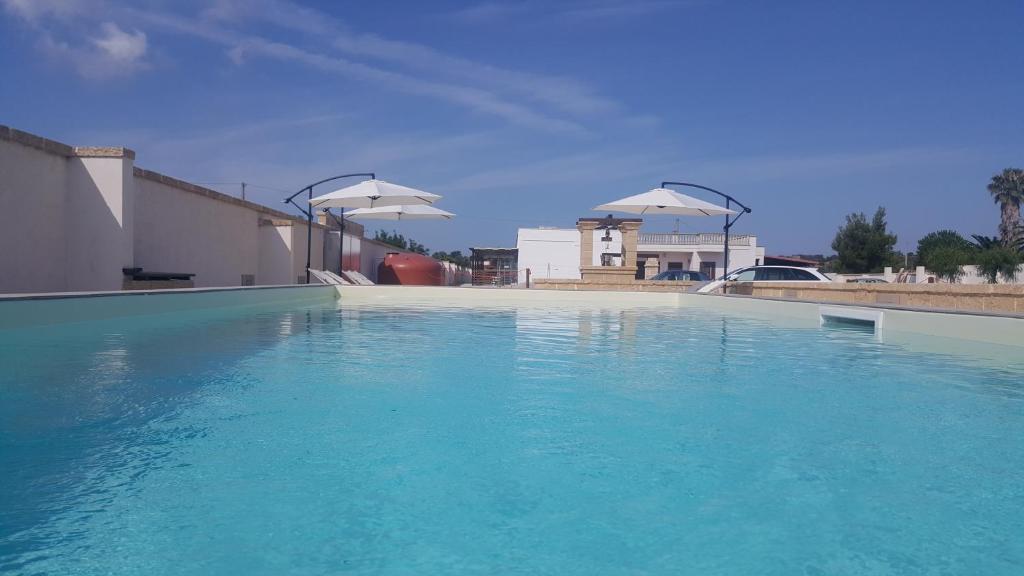 塔维亚诺Villa Silvia Luxury Residence的一个大的蓝色水池,有两把白色的伞