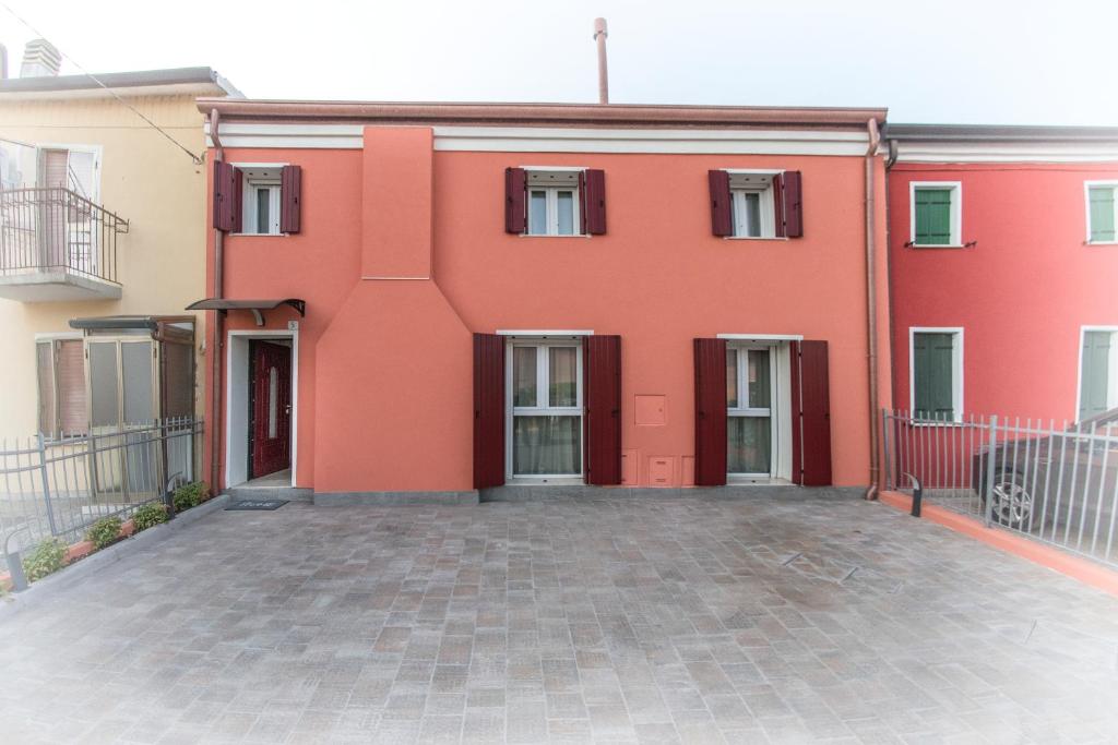 罗维戈ALL'ANTICO CAMPANILE的一座红色的建筑,前面有一个庭院