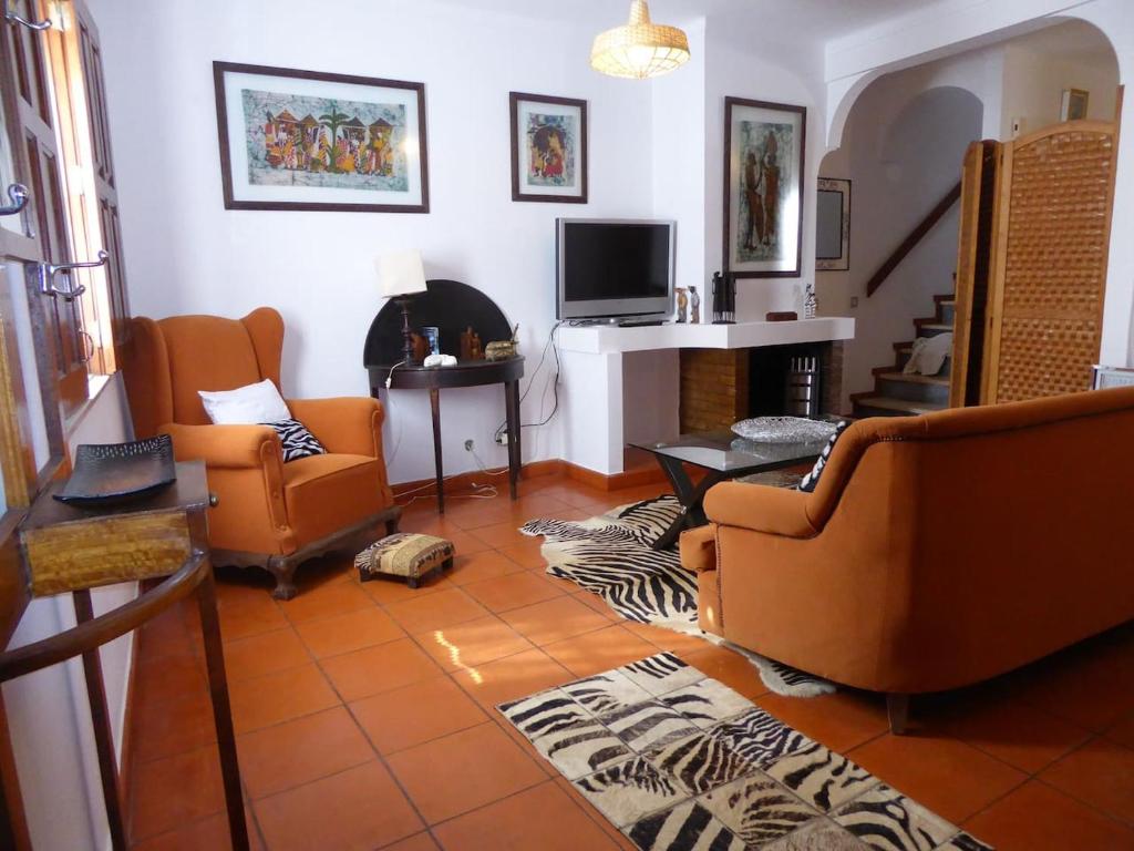 米尔芳提斯城CASA BERIMBAU的客厅配有橙色椅子和壁炉