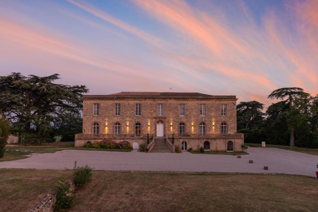 盖亚克Château de Tauzies, The Originals Relais的一座大砖砌建筑,背面有日落