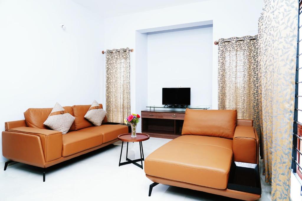 迈索尔UNNATHI SUITES的带沙发和电视的客厅