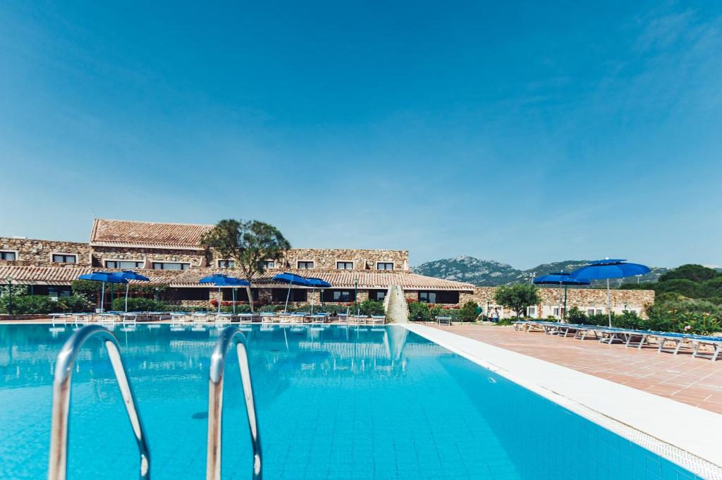 罗通多港Residence Hotel Nuraghe的一个带蓝色水和遮阳伞的游泳池
