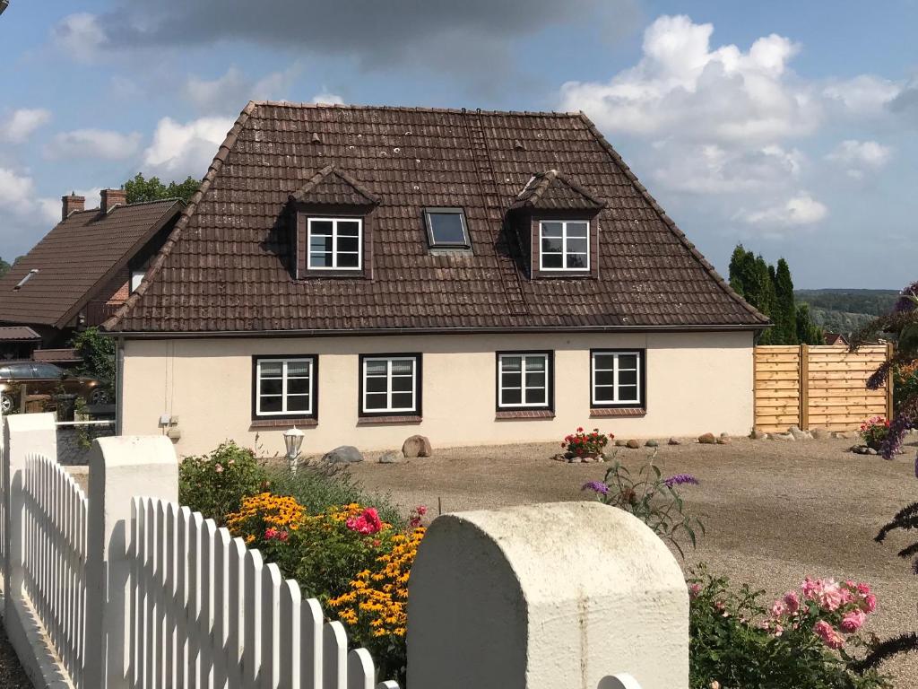 吕特延堡Ferienhaus Vogelberg的白色的房子,有棕色的屋顶和栅栏