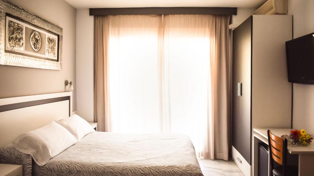 格拉纳达阿尔贝罗酒店的一间卧室设有一张床和一个大窗户