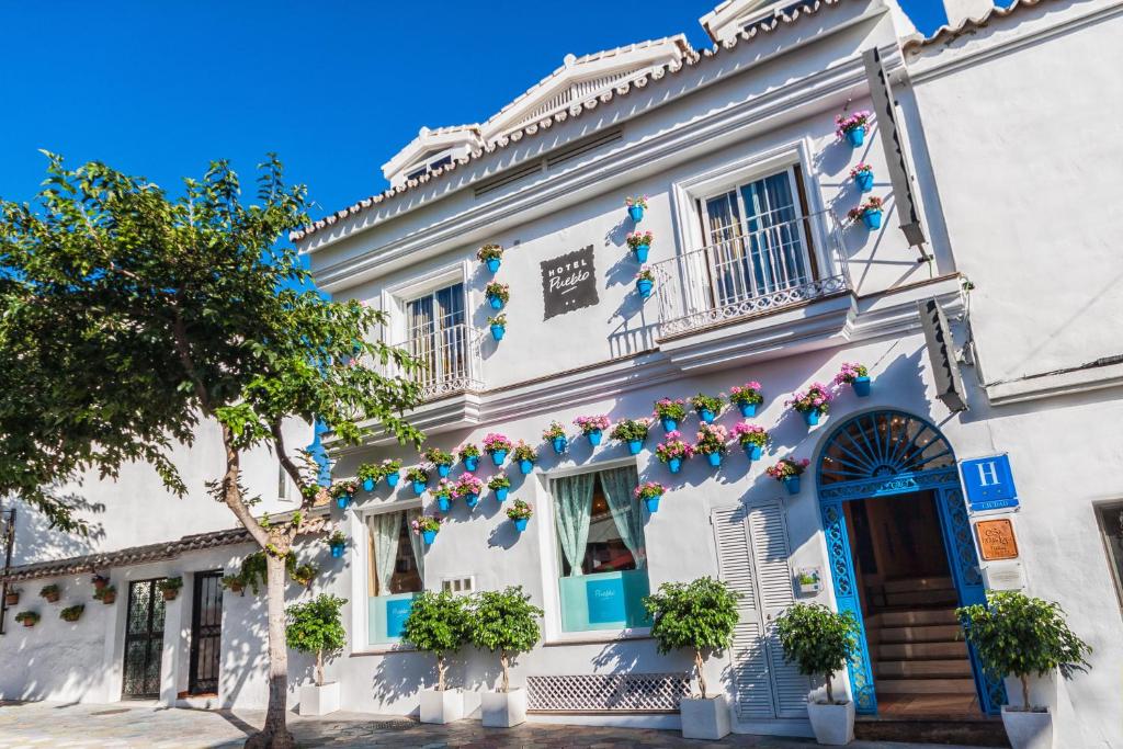 贝纳尔马德纳普韦布洛精品酒店的白色的建筑,有蓝色的门和鲜花