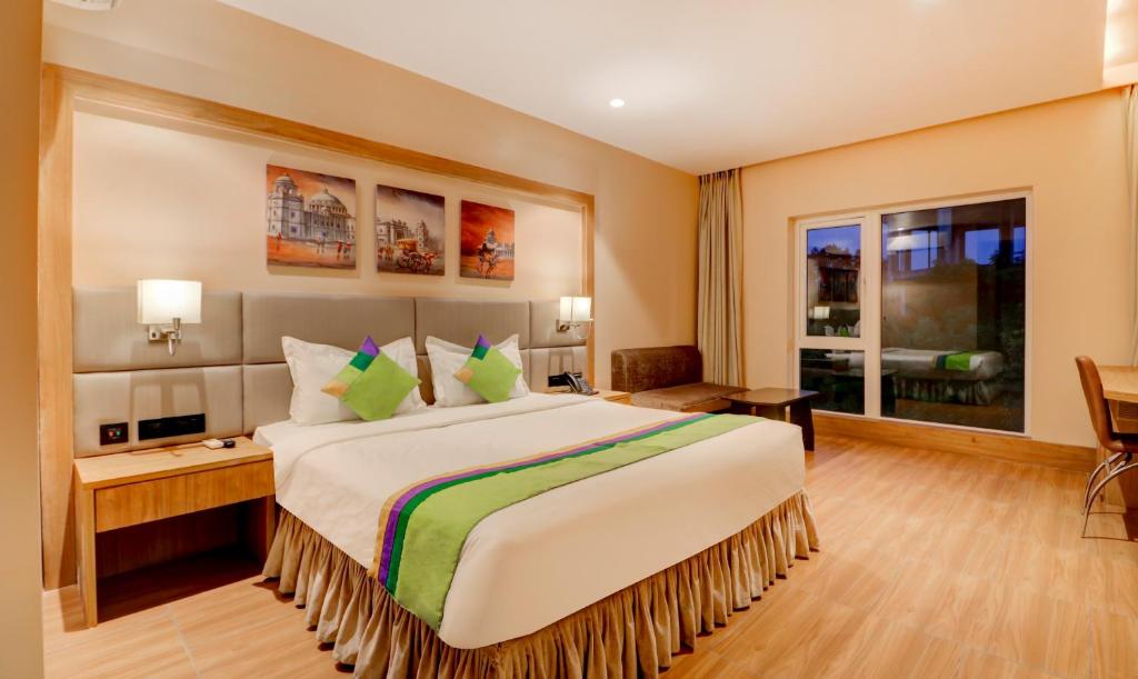 加尔各答Treebo Trend Radhe Palace的酒店客房设有一张大床和一张书桌。