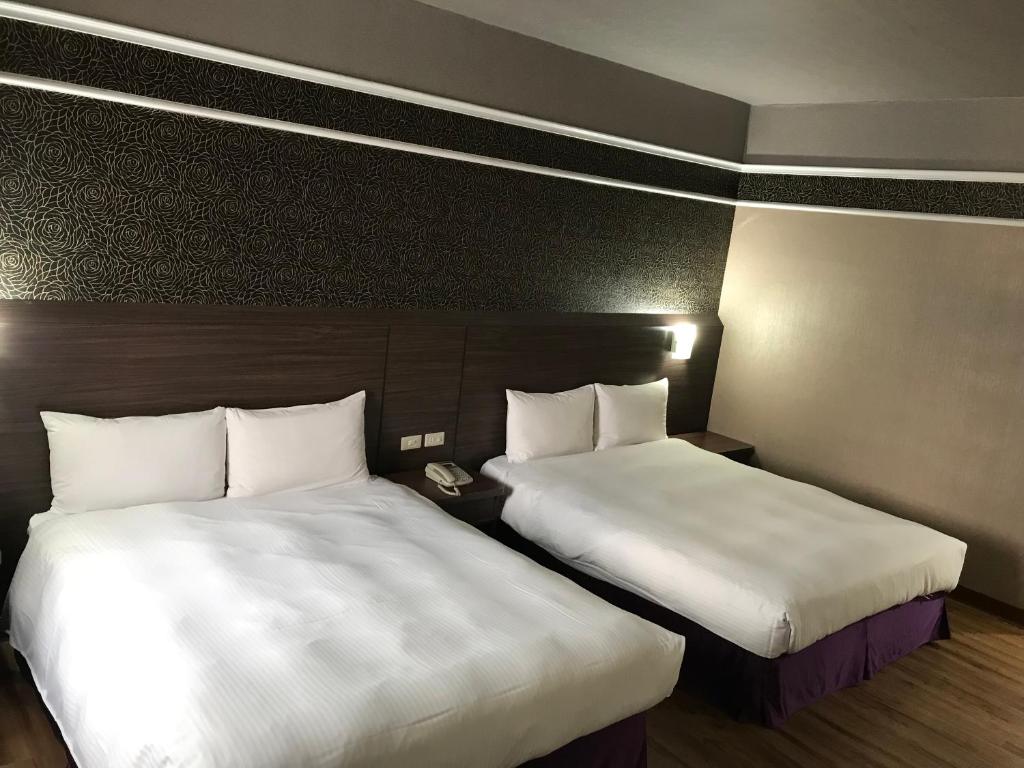 高雄龙翔商务大饭店的配有白色床单的酒店客房内的两张床