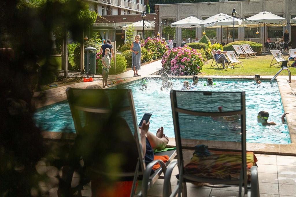 布鲁日布鲁日格林公园酒店的坐在游泳池前椅子上的人