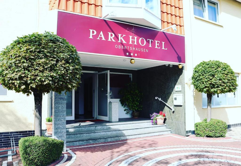 上茨豪森Parkhotel Obertshausen的上面有粉红色酒店标志的建筑