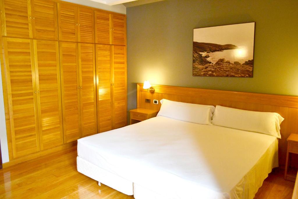 费罗尔Hotel Alda El Suizo的卧室配有白色的床和木制橱柜。