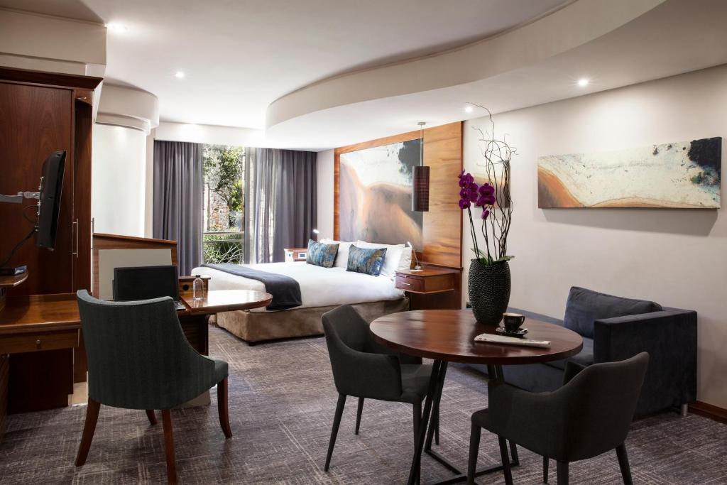 约翰内斯堡Seven Villa Hotel & Spa的酒店客房带一张床、一张桌子和椅子